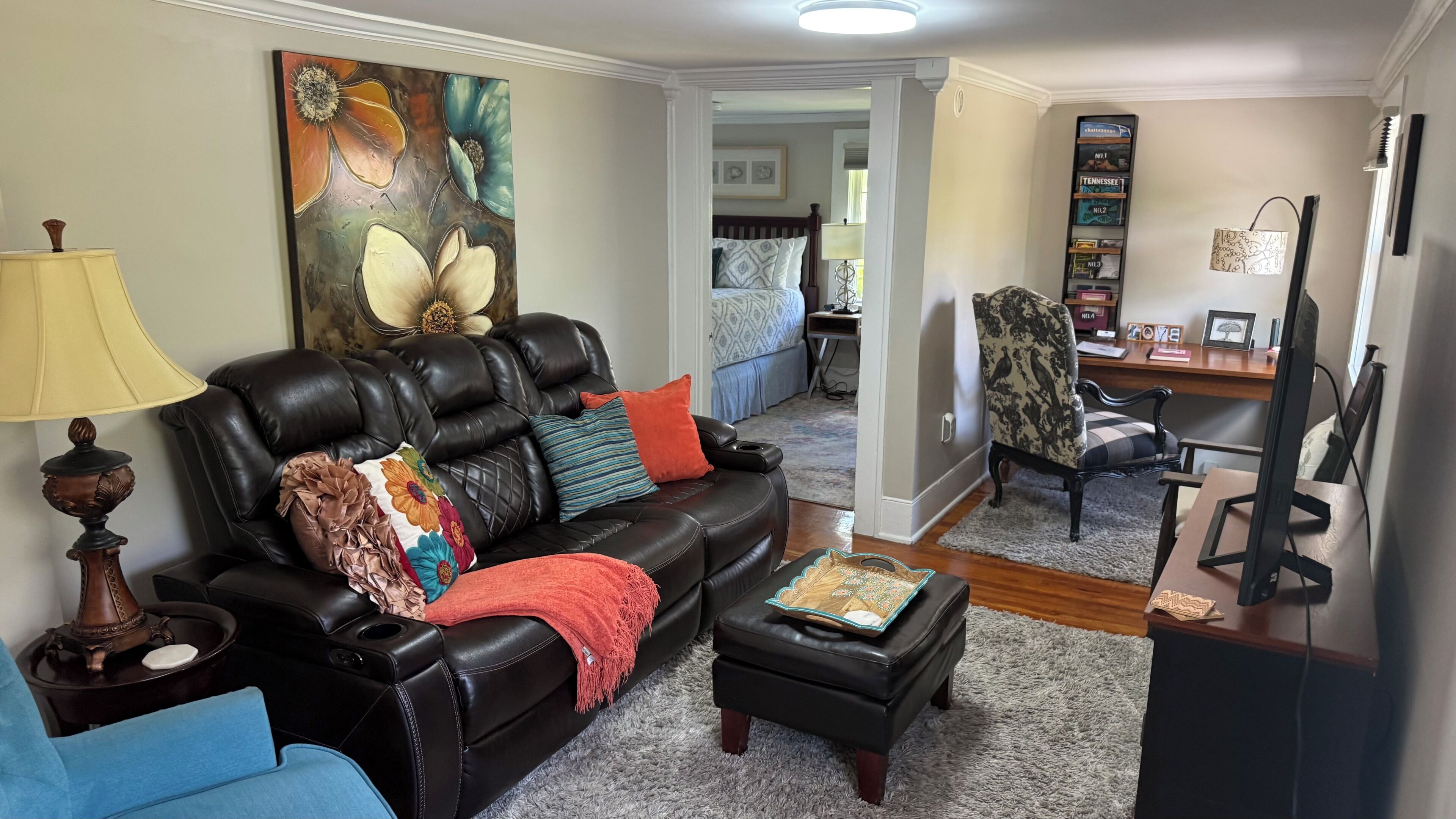 A living room with a leather sofa, a coffee table, and a painting on the wall.