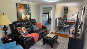 A living room with a leather sofa, a coffee table, and a painting on the wall.