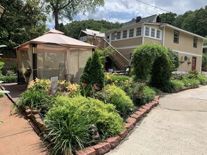 A house with a covered porch, a garden with various plants, and a staircase leading to the upper floor. - Bear House 1890, Lilly's Loft, Delightful, Upgraded amenities, Walk to Cafes (Chattanooga)