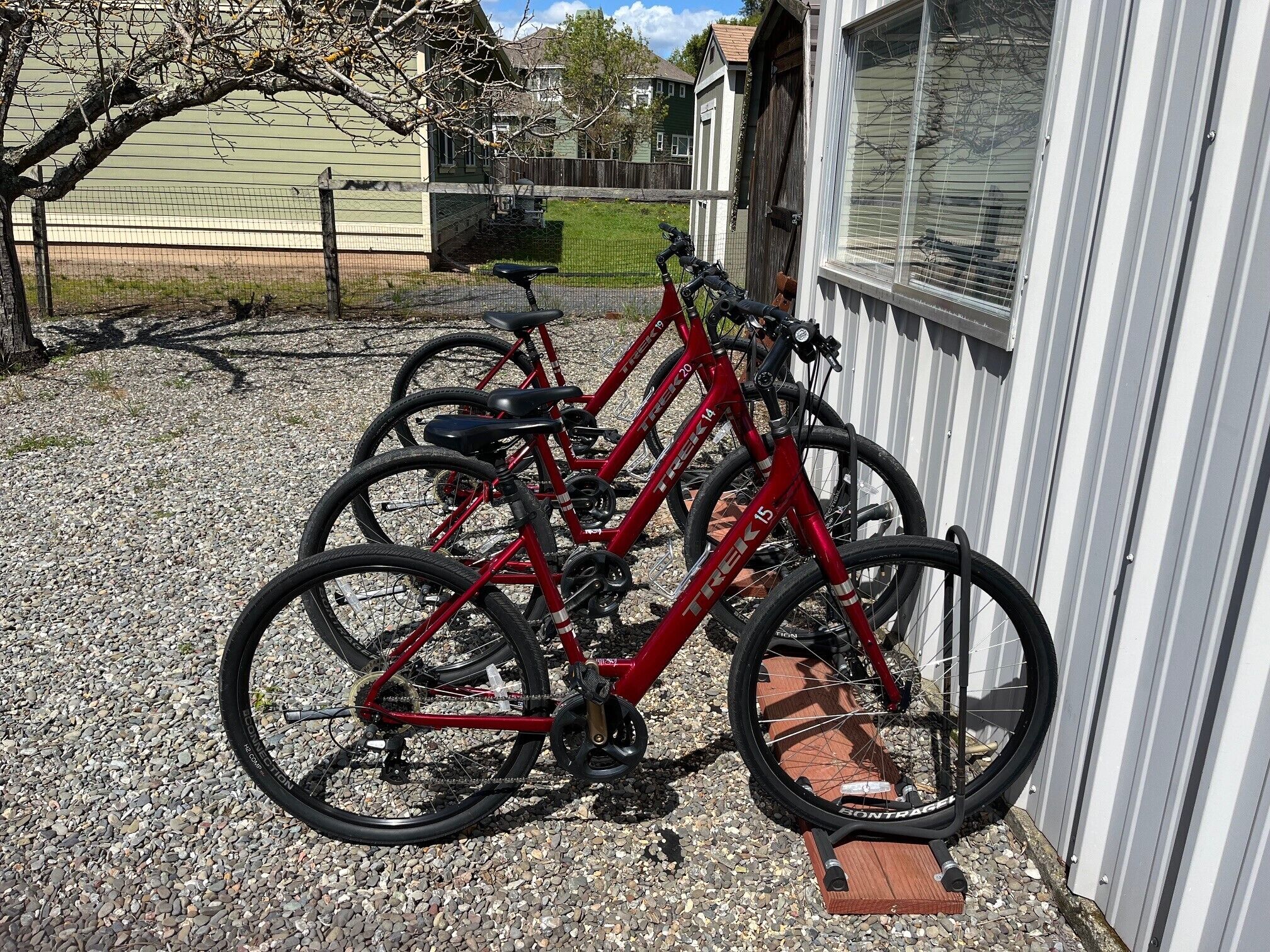 A red bicycle parked in front of a building with a brick base.