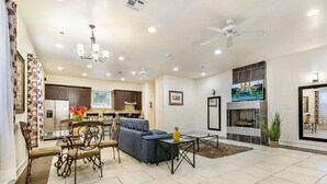 A spacious living room with a fireplace, a dining area with a chandelier, and a kitchen in the background. - 15% OFF Monthly |10% OFF Weekly-Carondelet Street Cozy Condos (New Orleans)
