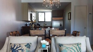 A modern living room with two sofas, a small side table, and a chandelier.