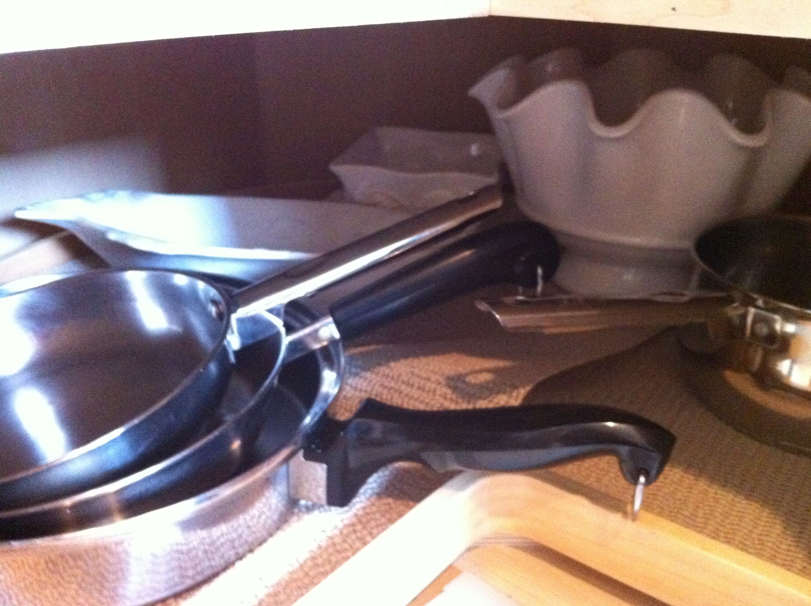 Un comptoir de cuisine avec une poêle, une spatule et un récipient blanc.