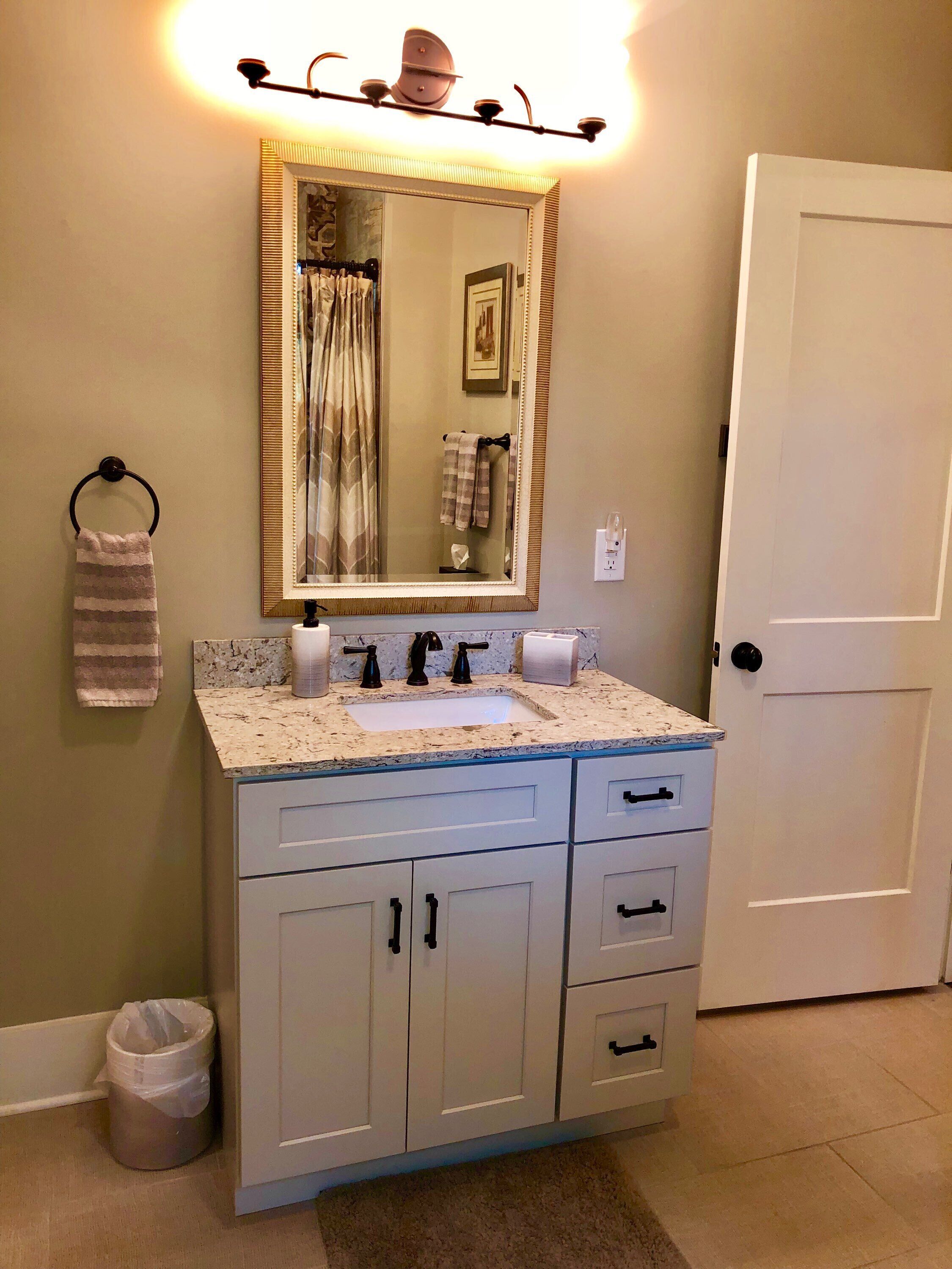 A bathroom with a sink, mirror, towel rack, and a door.