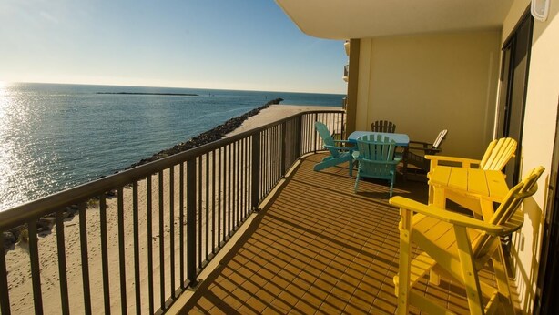 A balcony with a view of the sea, featuring a wooden deck, a railing, and two chairs. - Awesome Views!!! Watch the sail boats & seagulls. Two pools. Two hot tubs.
. (Orange Beach)