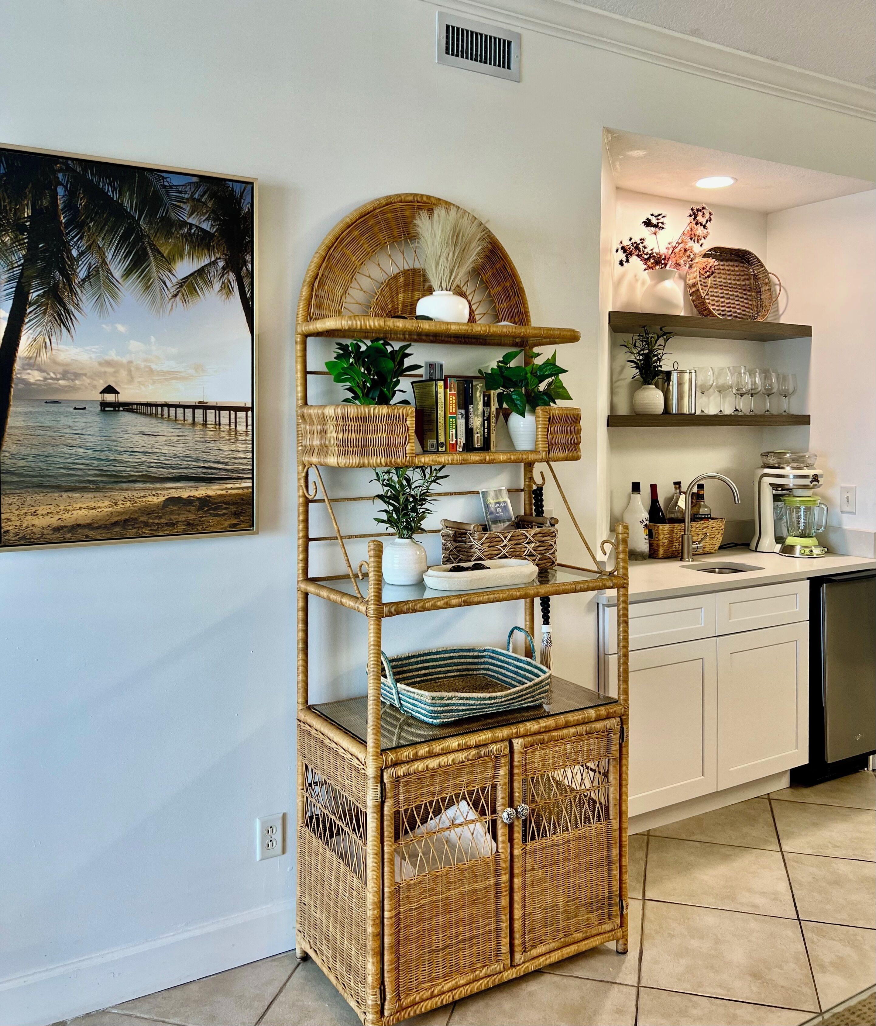 Una cucina con un'unità a scaffali in vimini, un quadro raffigurante una spiaggia e vista sull'oceano.
