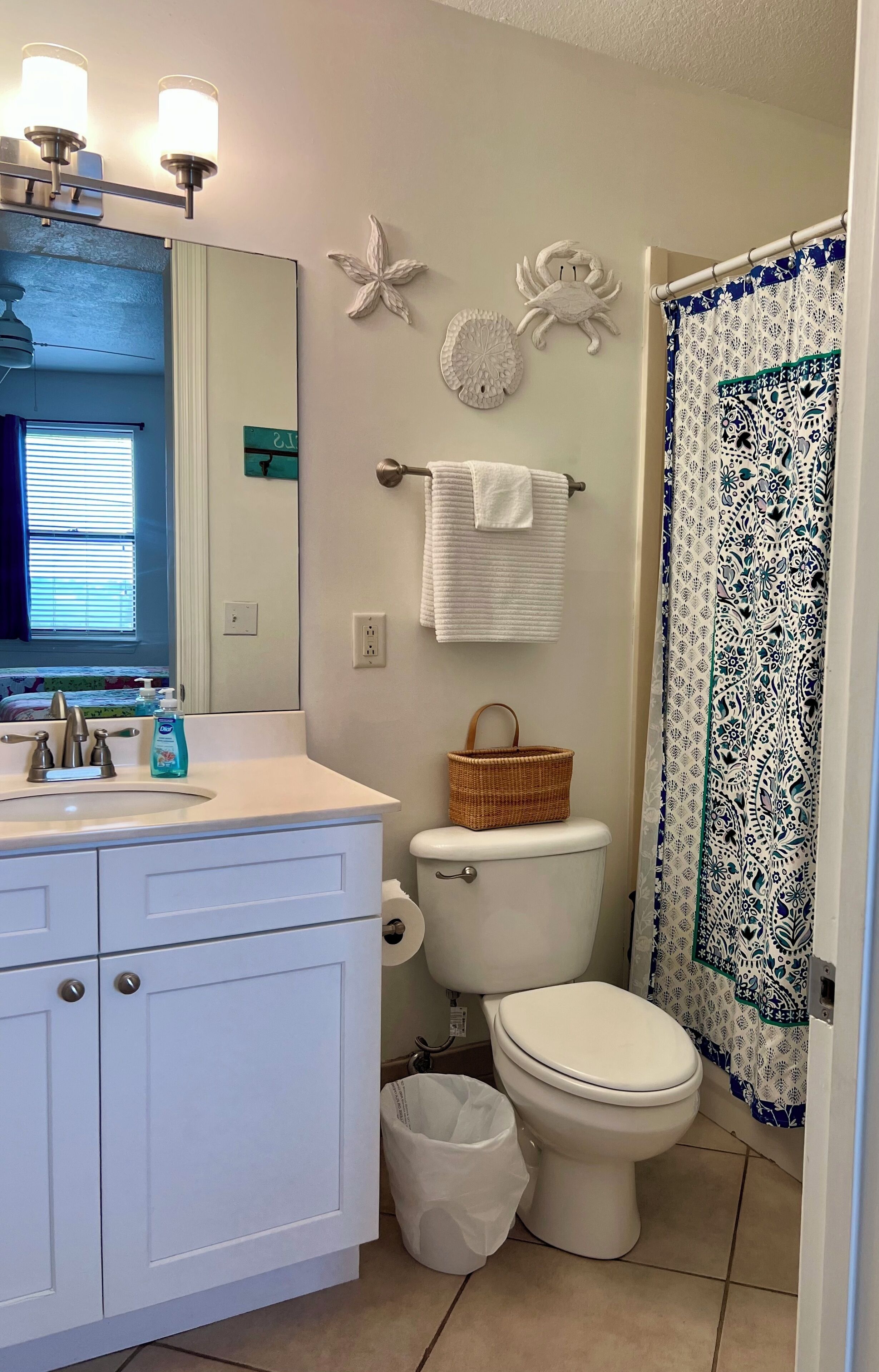 A bathroom with a white sink, a toilet, a basket, and a shower curtain.