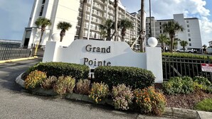 A hotel entrance with a sign reading "Grand Pointe," surrounded by palm trees and a well-maintained garden. - Awesome Views!!! Watch the sail boats & seagulls. Two pools. Two hot tubs.
. (Orange Beach)