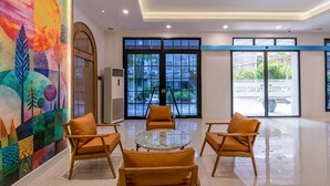 A spacious lobby with a large mural, a glass door leading outside, and a round table with chairs. - Palago Hotel, Binh Thanh District (Ho Chi Minh City)