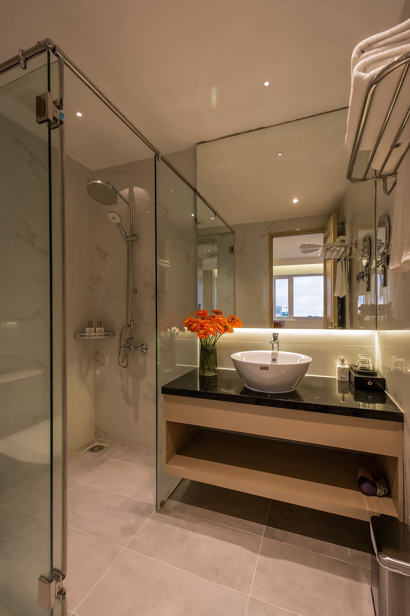 A modern bathroom with a glass-enclosed shower, a white vessel sink, and a mirror above the sink.