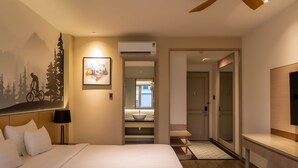 A hotel room with a bed, a nightstand with a lamp, a painting, an air conditioning unit, a bathroom with a sink and mirror, and a TV. - Palago Hotel, Binh Thanh District (Ho Chi Minh City)