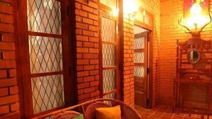 A cozy room with a wicker sofa, a wooden table, and a brick wall with a decorative mirror. - Plantation Retreat (Pathadumbara)