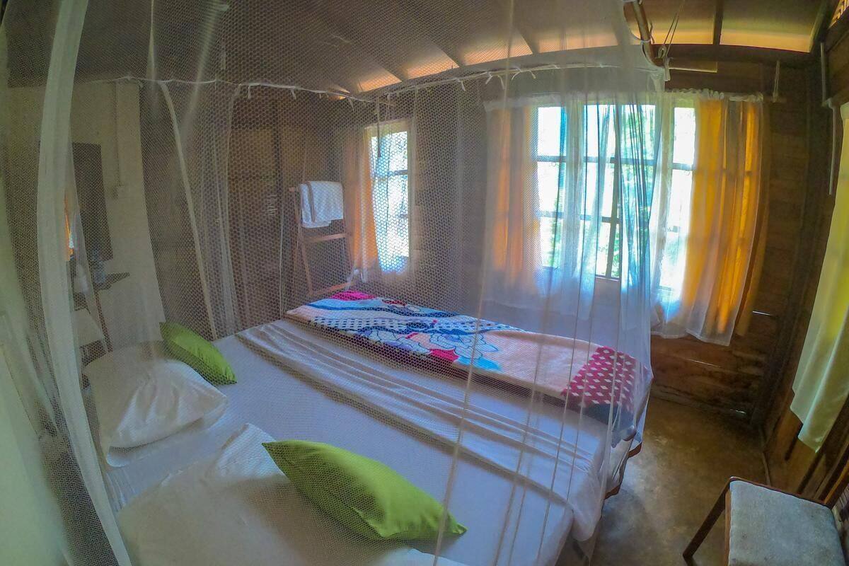 Ein Zimmer mit zwei Betten, jedes mit Moskitonetz, und einem Sessel.