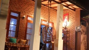 A brick building with a pool, a hanging chair, and a table with chairs. - Plantation Retreat (Pathadumbara)