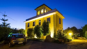 A two-story yellow building with a car parked in front.
