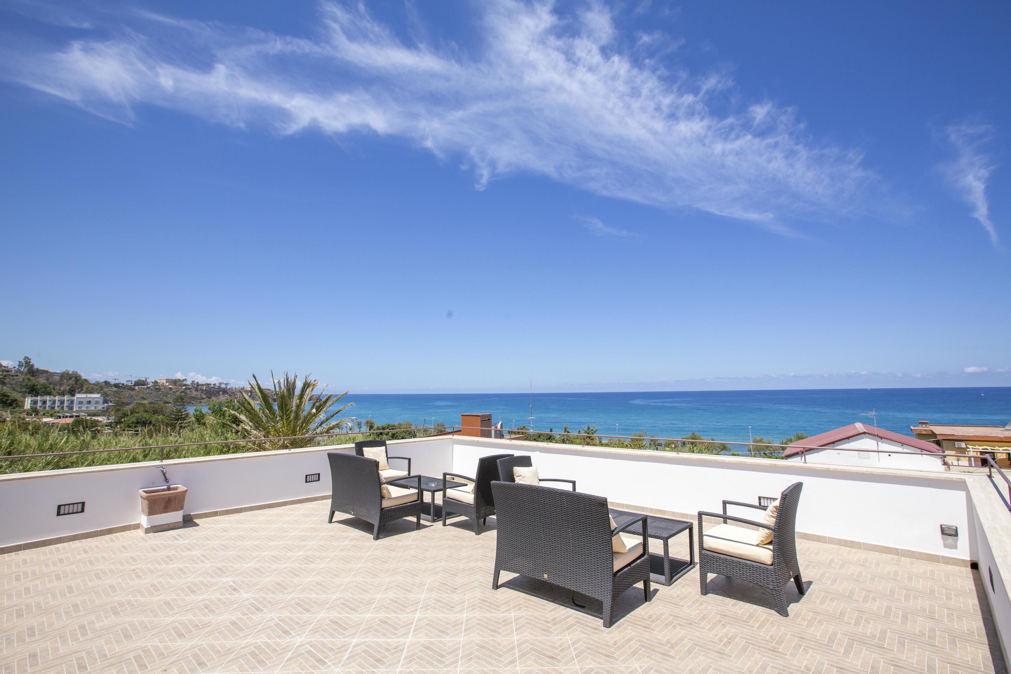 A rooftop terrace with outdoor furniture and a view of the ocean.