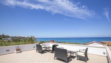 A rooftop terrace with outdoor furniture and a view of the ocean.