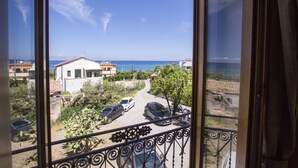 A balcony with a view of a coastal road, parked cars, and houses.