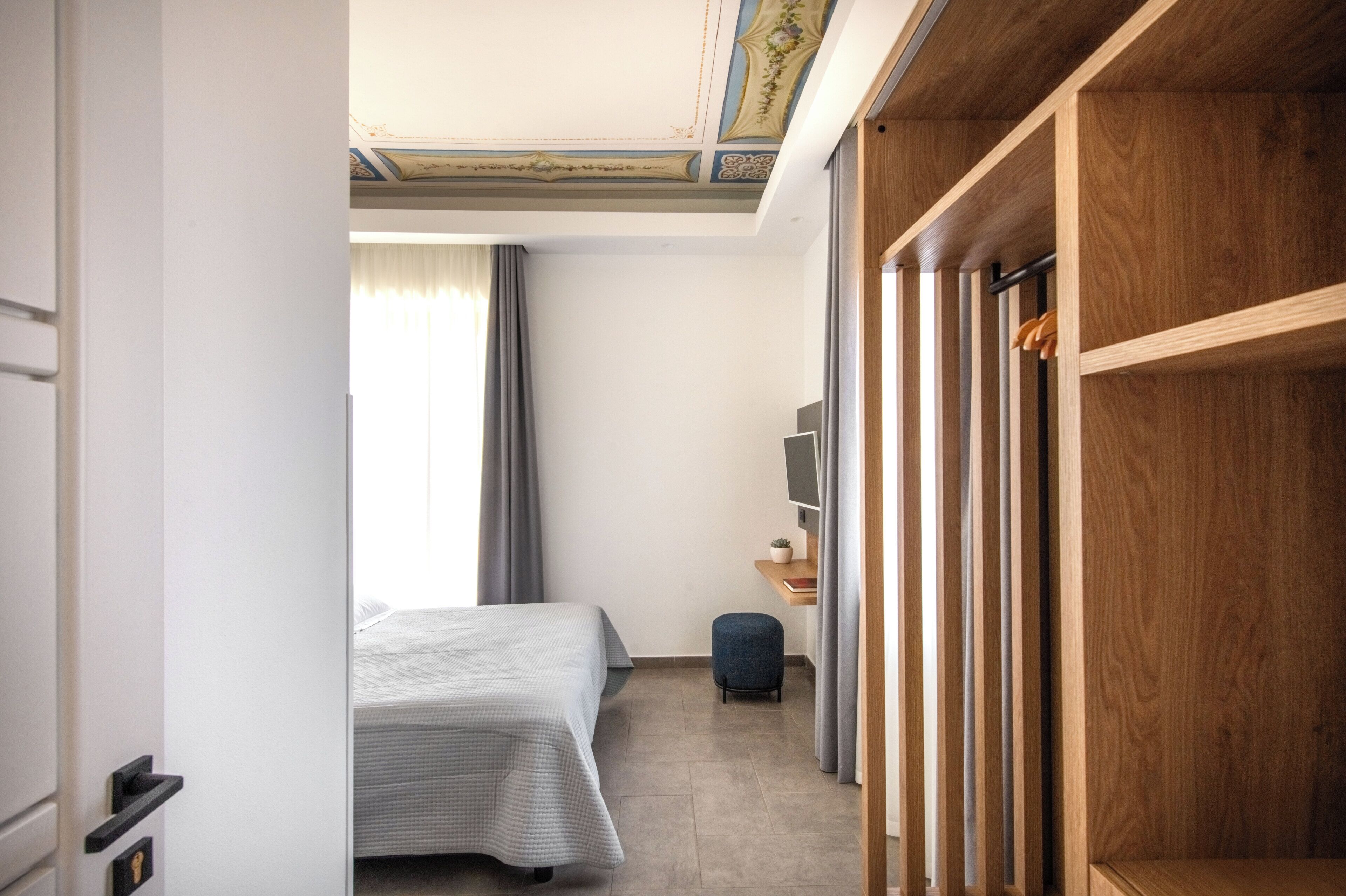 A hotel room with a bed, a desk, a television, and a wardrobe.