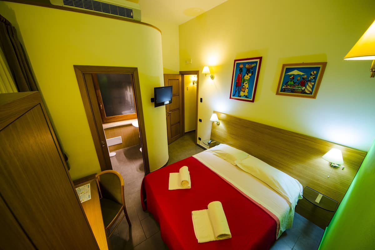 A hotel room with a bed, a television, a desk, and a chair.