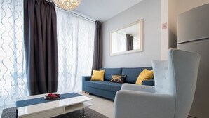 A modern living room with a sofa, a chair, a coffee table, and a large window with curtains. - Sweethome26 Luxury Apt With Parking (Tel Aviv)