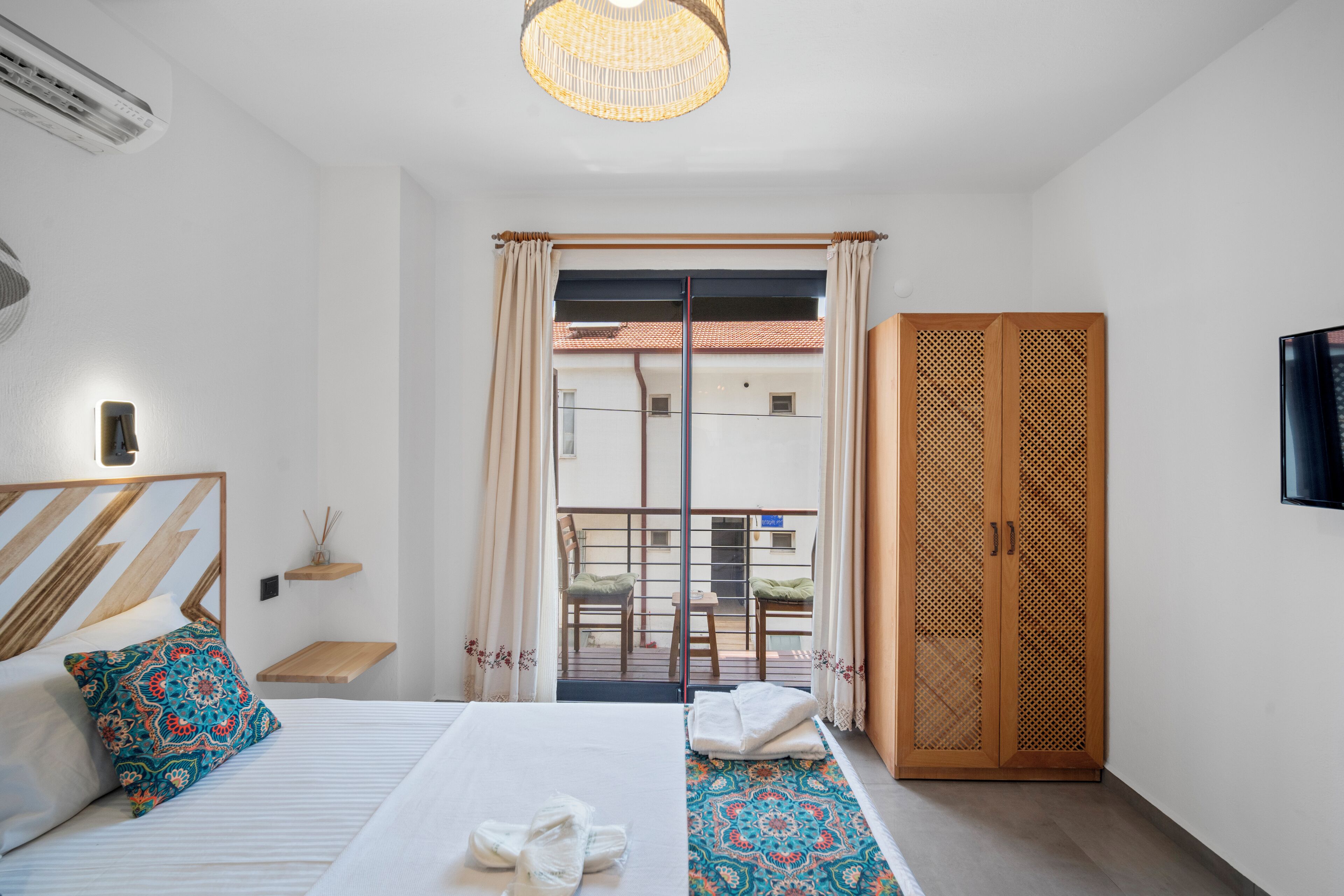 Una camera d'albergo con un letto, un armadio, un balcone vista e una televisione a parete.