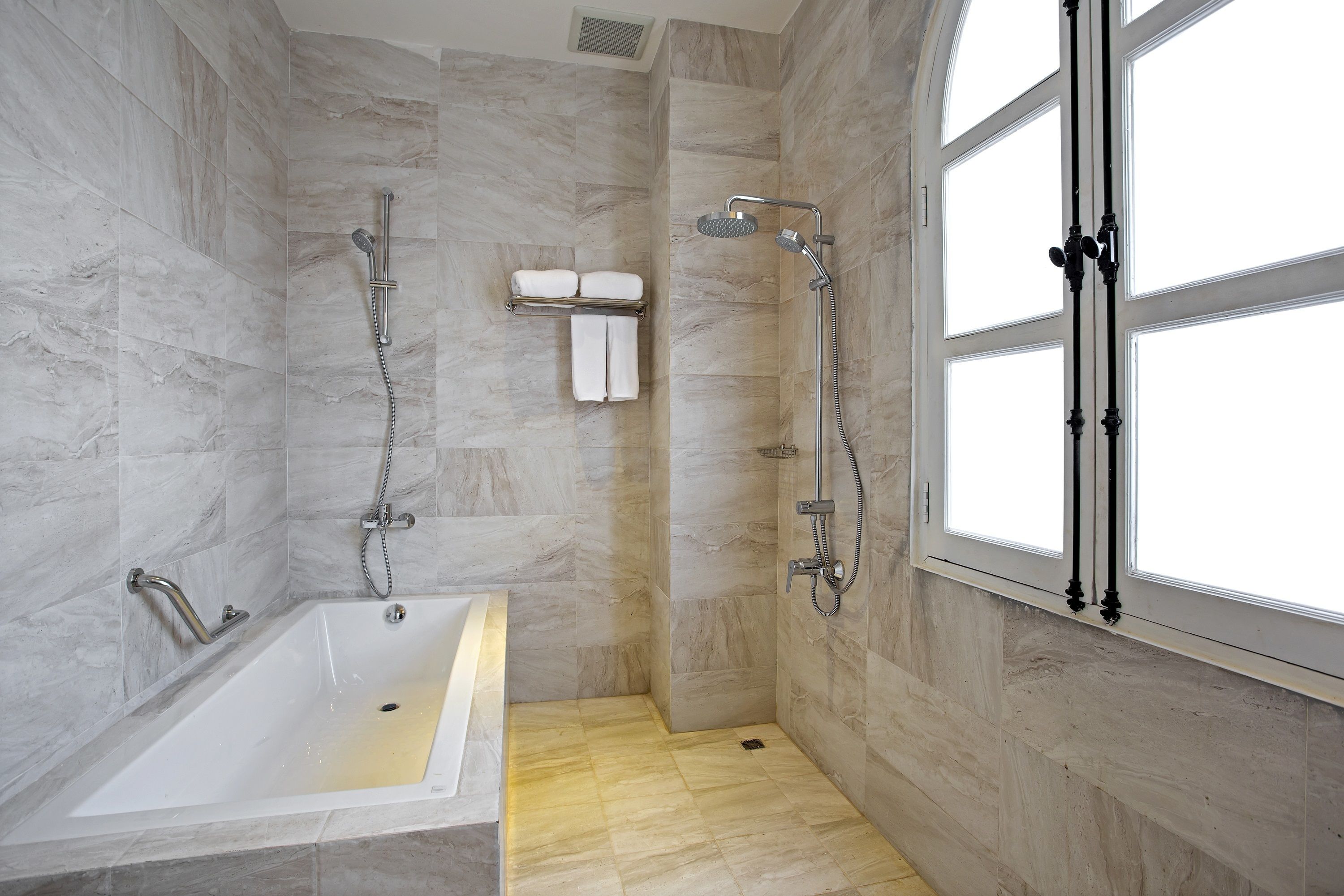 A modern bathroom with a bathtub, shower, and large windows.