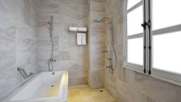A modern bathroom with a bathtub, shower, and large windows.