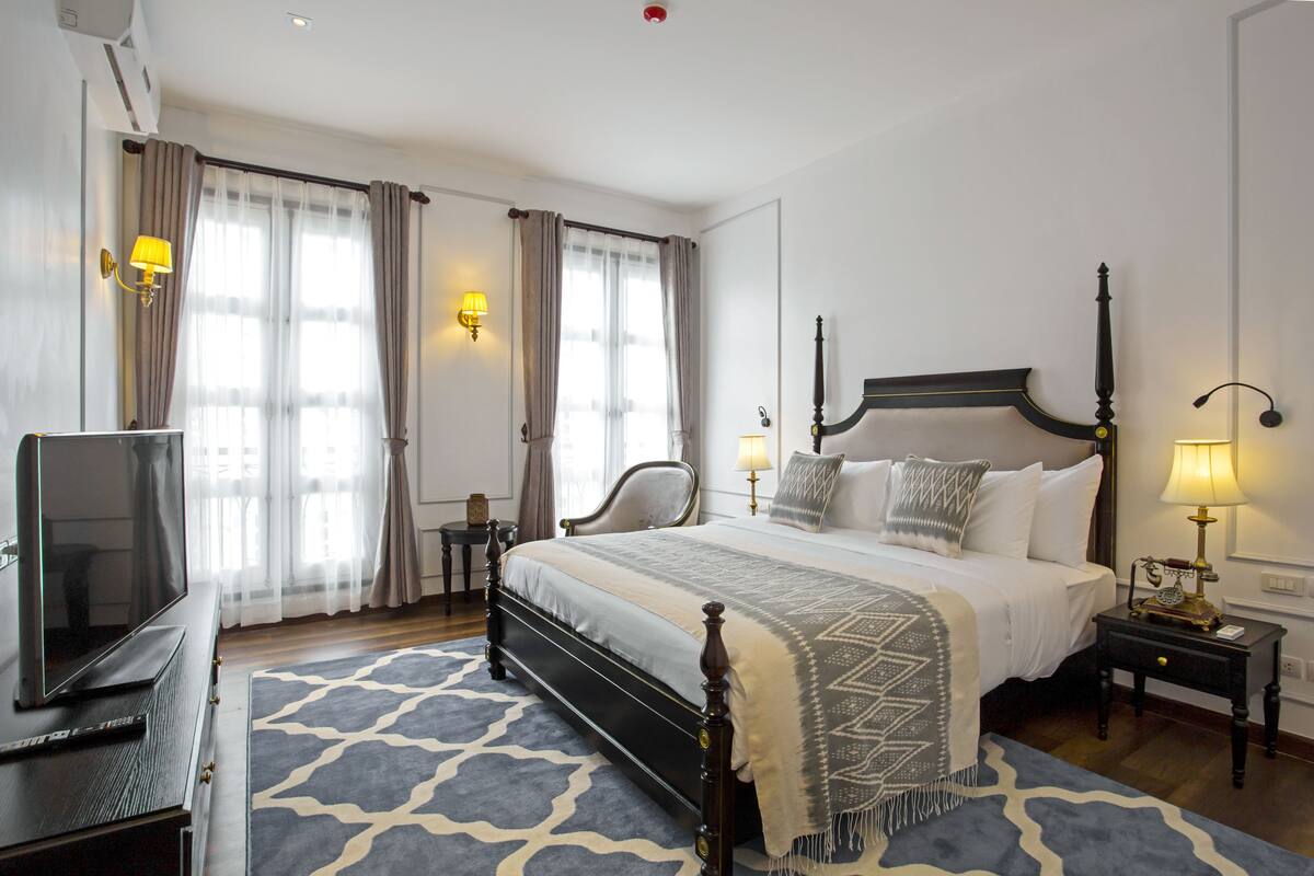 Ein Hotelzimmer mit einem großen Bett, einem Fernseher und einem Schreibtisch mit einer Lampe.
