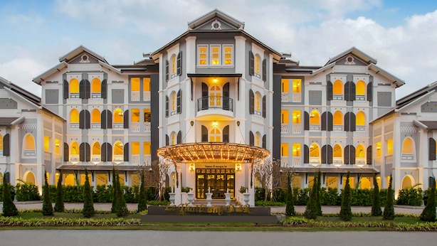 Um hotel grande, com vários andares, fachada simétrica, múltiplas varandas e entrada central com marquise.