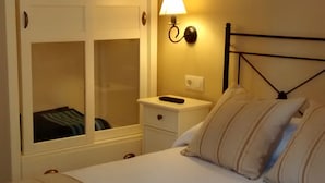 Ein Schlafzimmer mit Bett, Nachttisch, Schrank und einer Wandlampe.