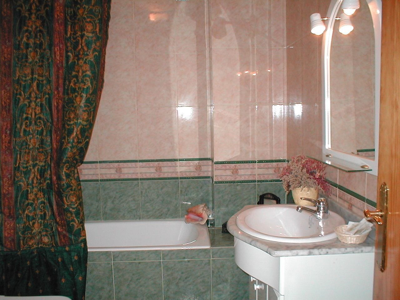 A bathroom with a bathtub, sink, and mirror.