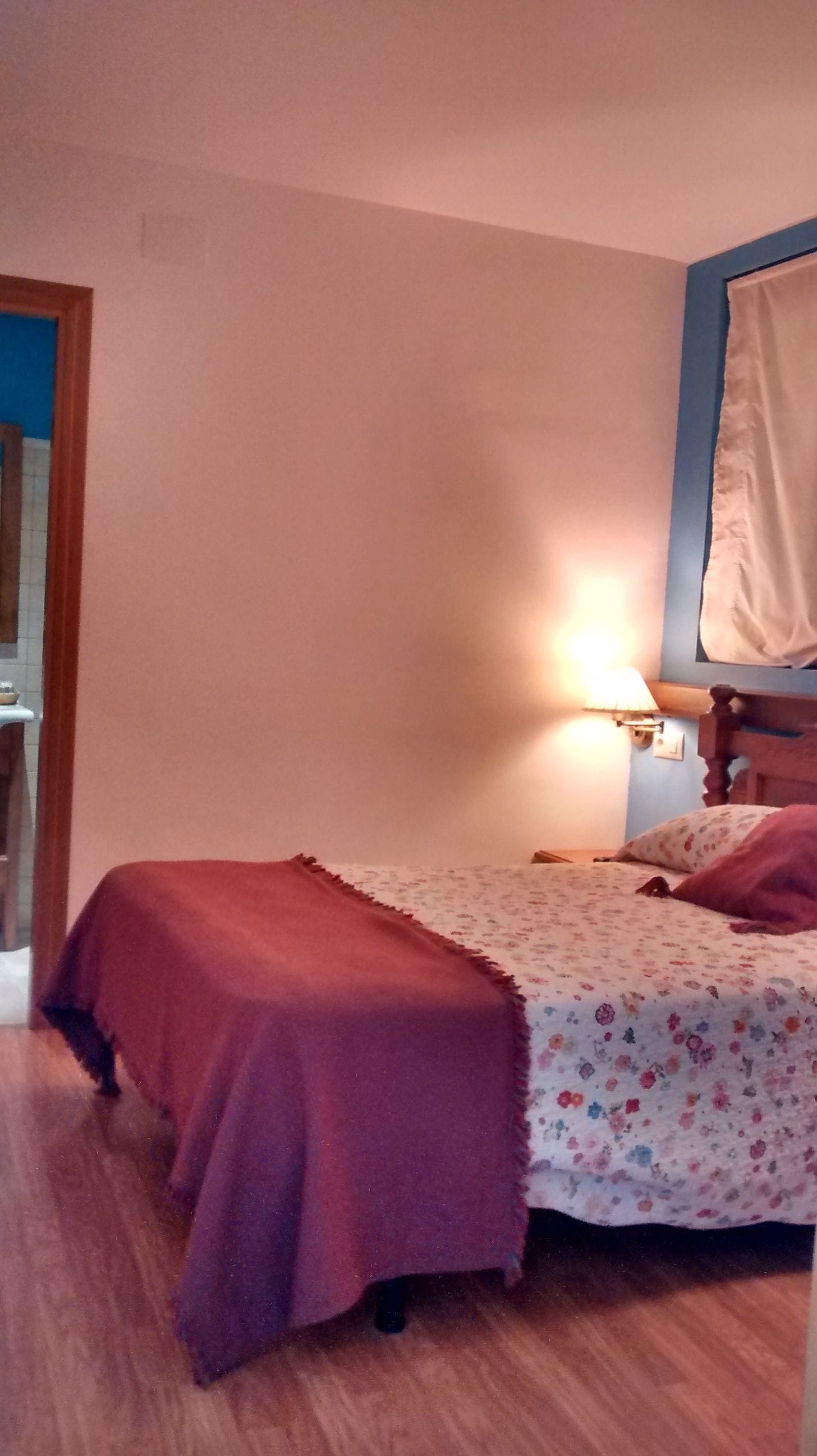 Een slaapkamer met twee bedden, een nachtkastje, een lamp en een raam met gordijn.