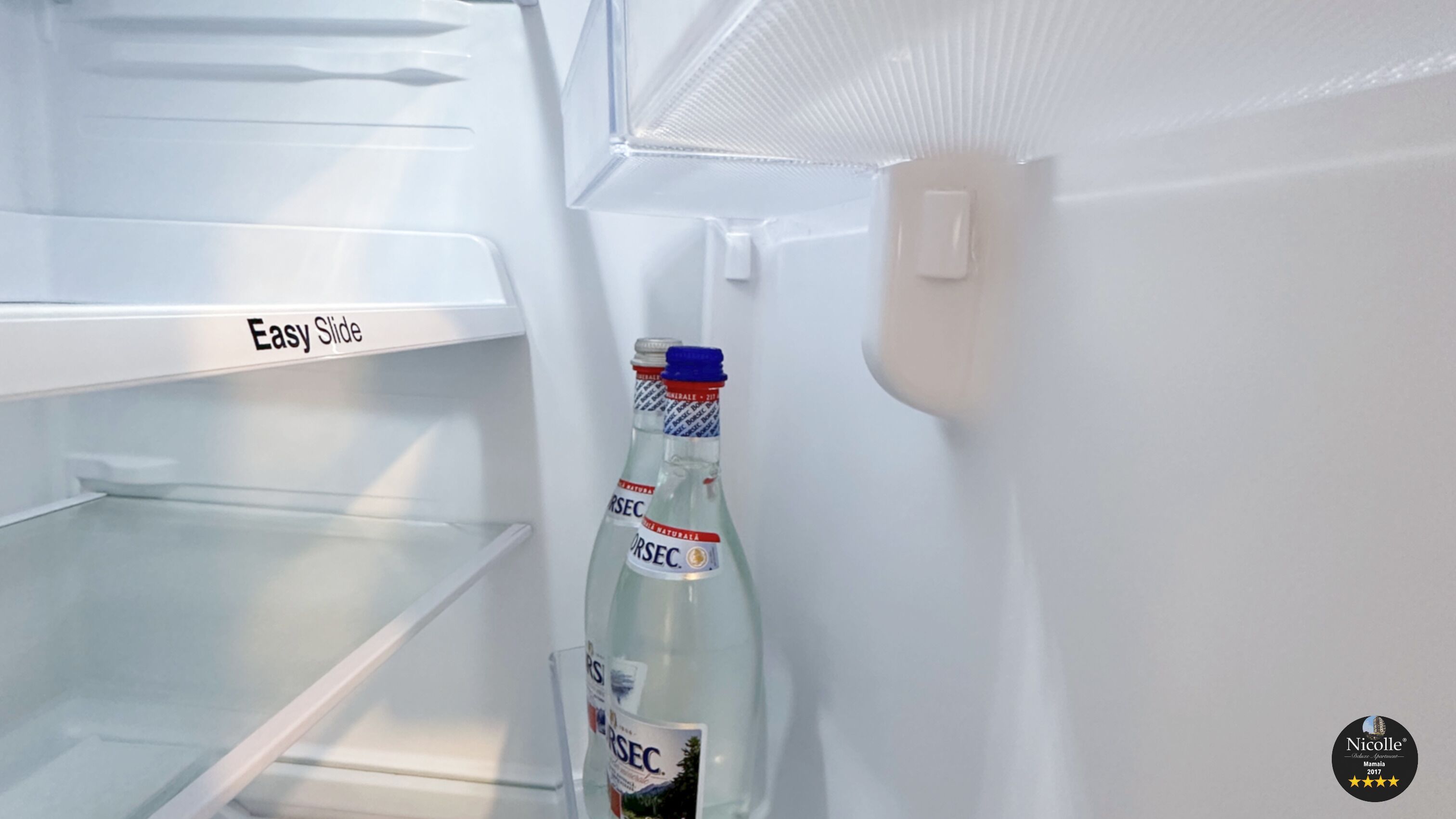 An open refrigerator with a bottle of water on the door shelf.