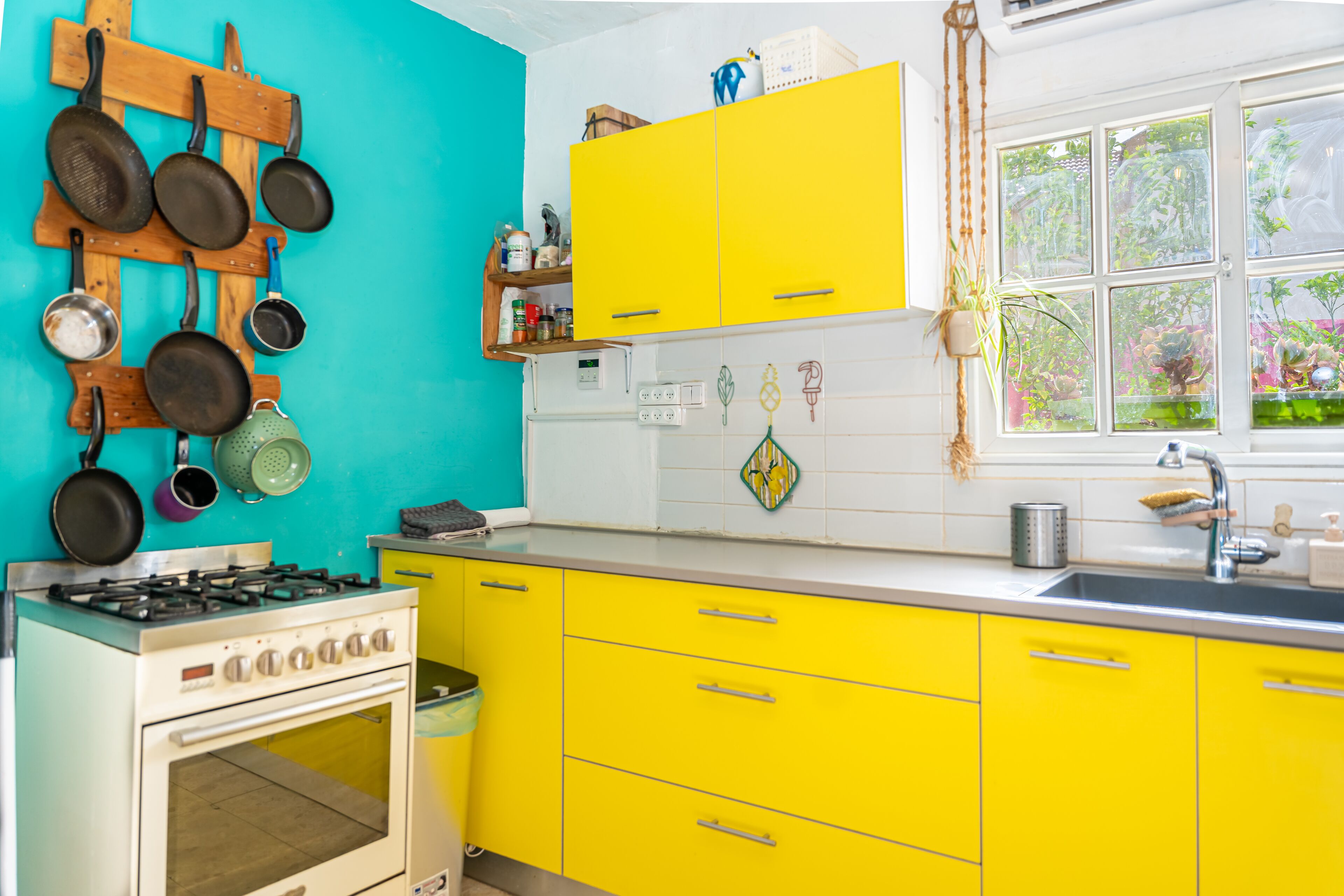 Una cocina con gabinetes amarillos, una estufa y una ventana con vista a follaje.