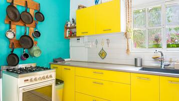 Una cocina con gabinetes amarillos, una estufa y una ventana con vista a follaje.