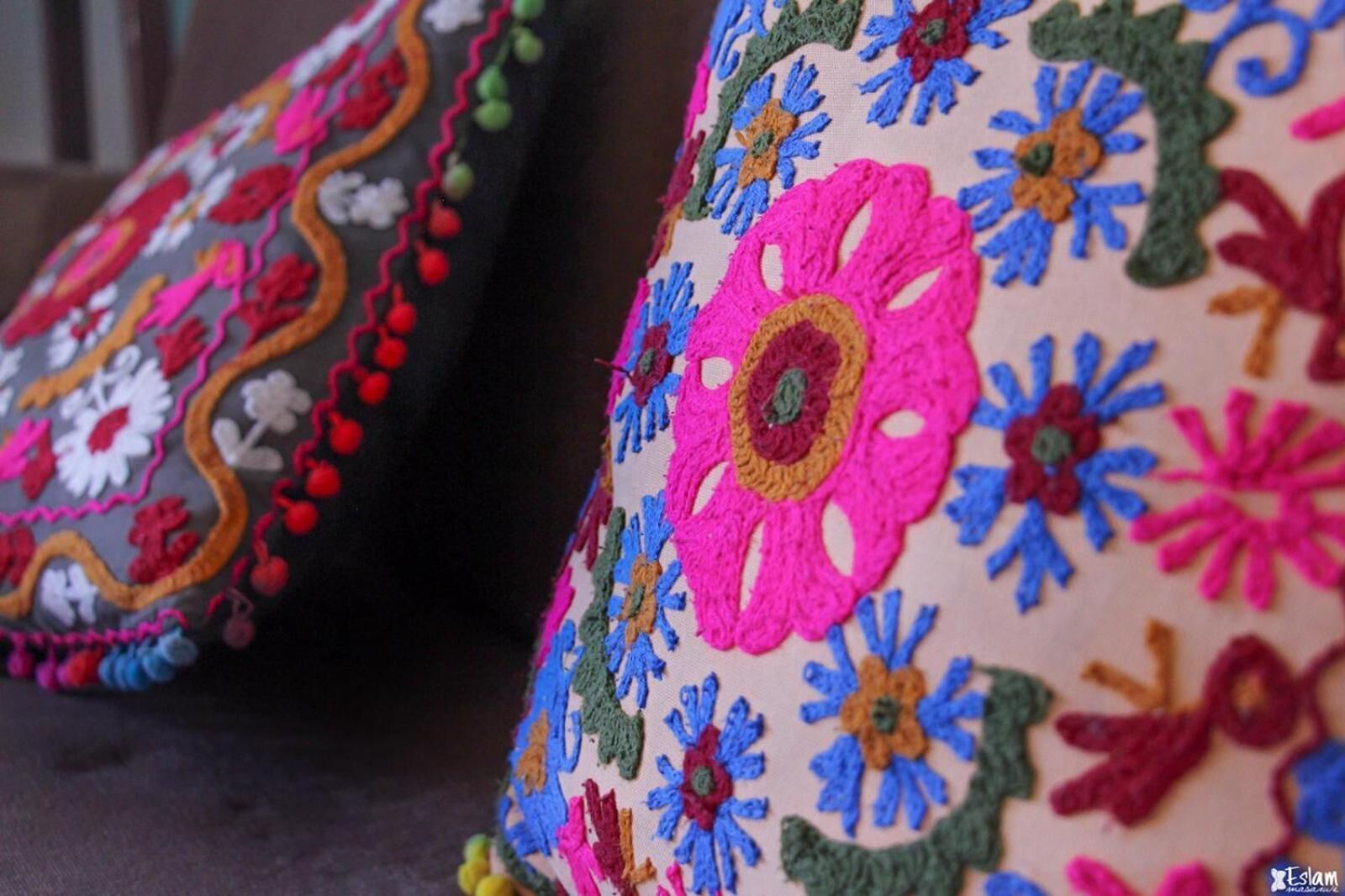 A close-up of a pillow with colorful floral embroidery.