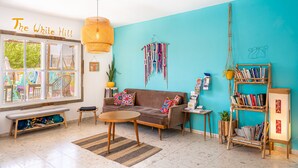Un salón acogedor con una pared azul turquesa, un sofá marrón, un banco de madera y una estantería.