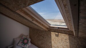 Una habitación con tragaluces, vigas de madera y vistas al paisaje desértico.