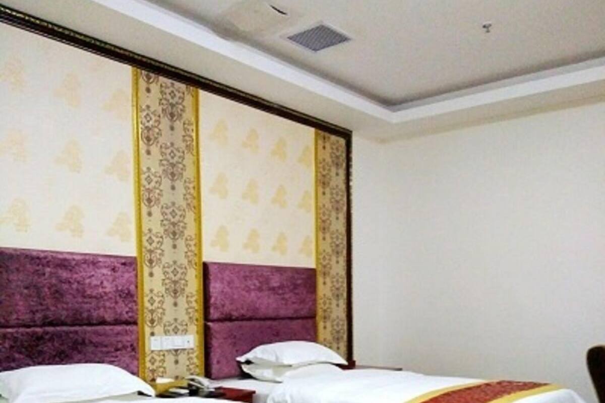 A hotel room with two beds, each with a white and red bedspread, and a purple headboard.