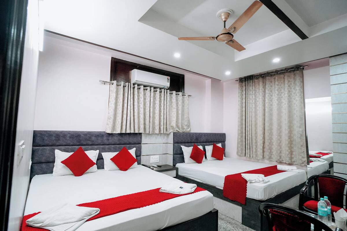 A hotel room with two beds, a ceiling fan, an air conditioning unit, and a red and white color scheme.