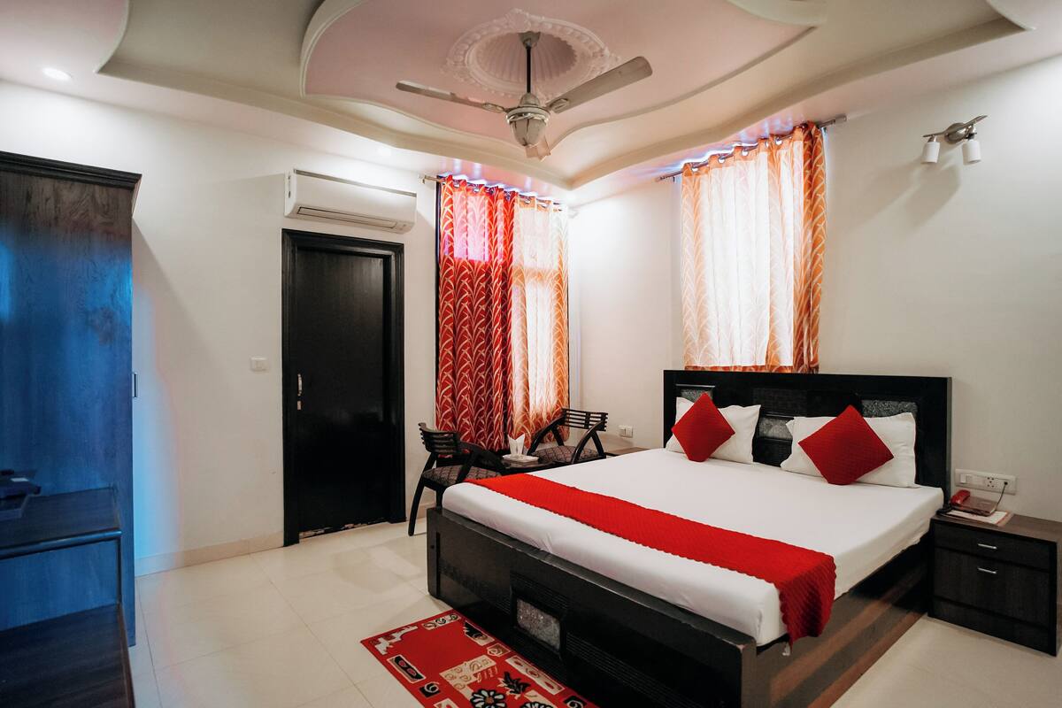 A bedroom with a bed, a ceiling fan, a nightstand, a chair, and a door.