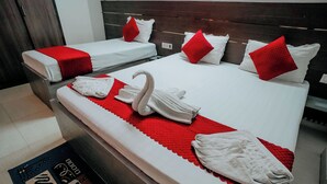 Habitación de hotel con dos camas, ropa de cama roja y blanca, y una decoración de toallas con forma de cisne.
