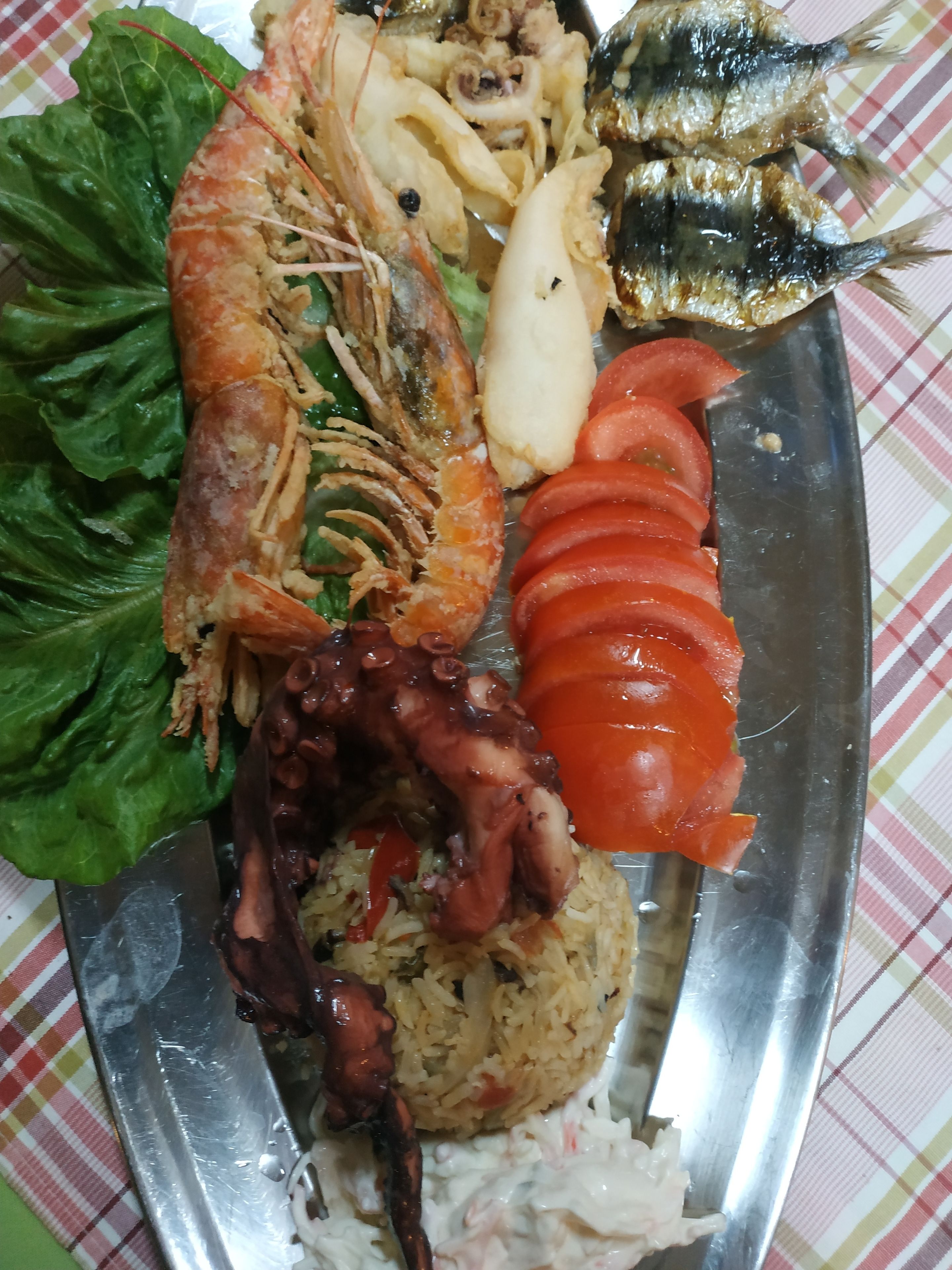Een bord eten met garnalen, vis, rijst en groenten.