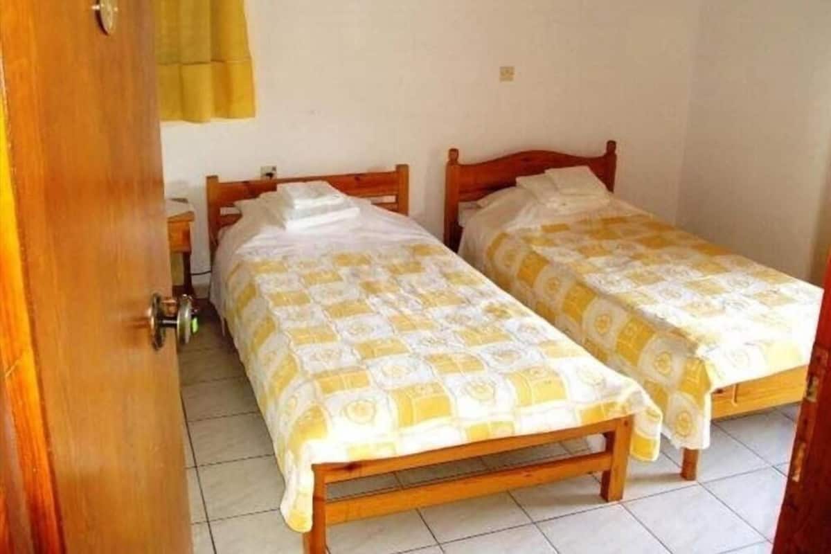 Een kamer met twee houten bedden, elk met een beddengoed met een patroon.