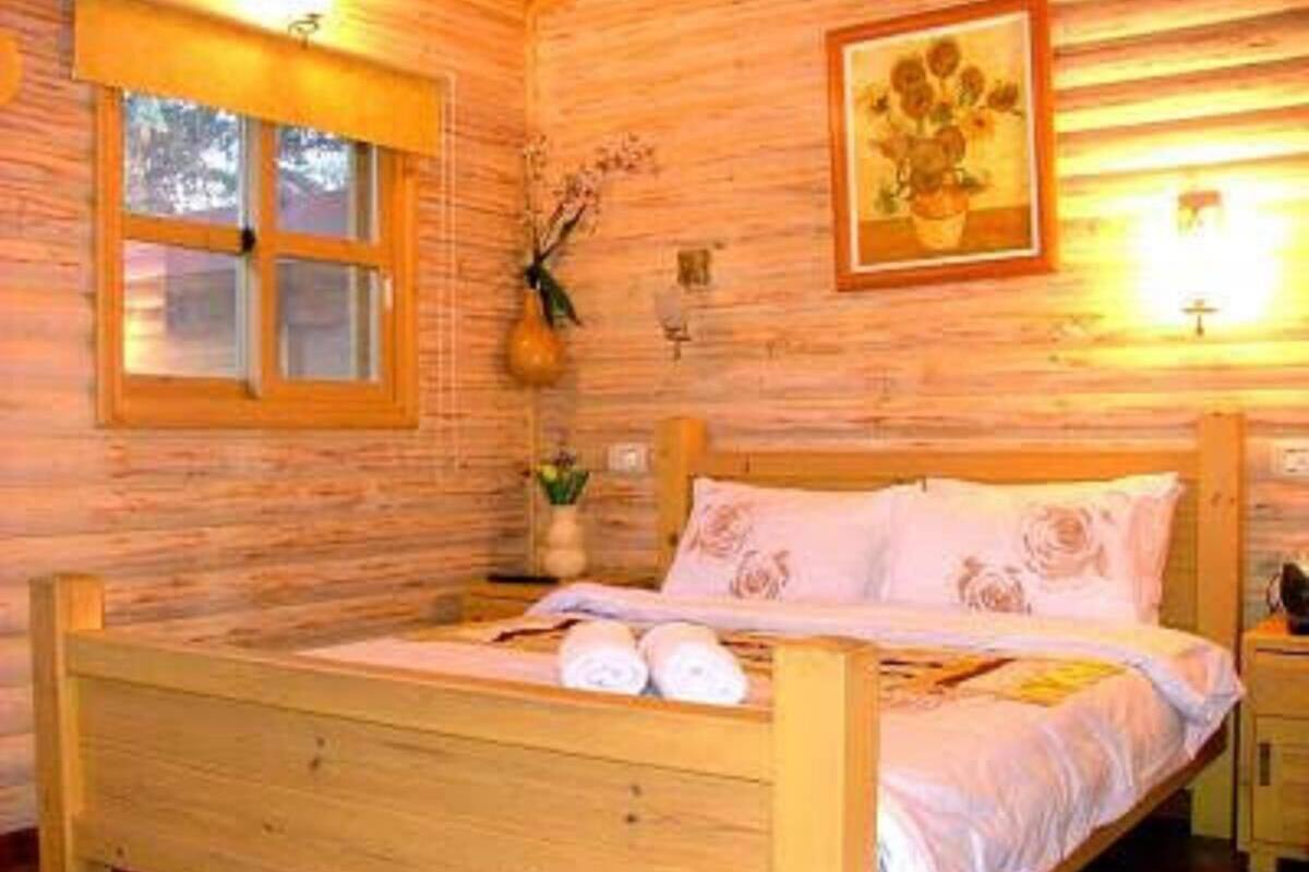 A wooden cabin bedroom with a bed, a window, and a wall-mounted light fixture.