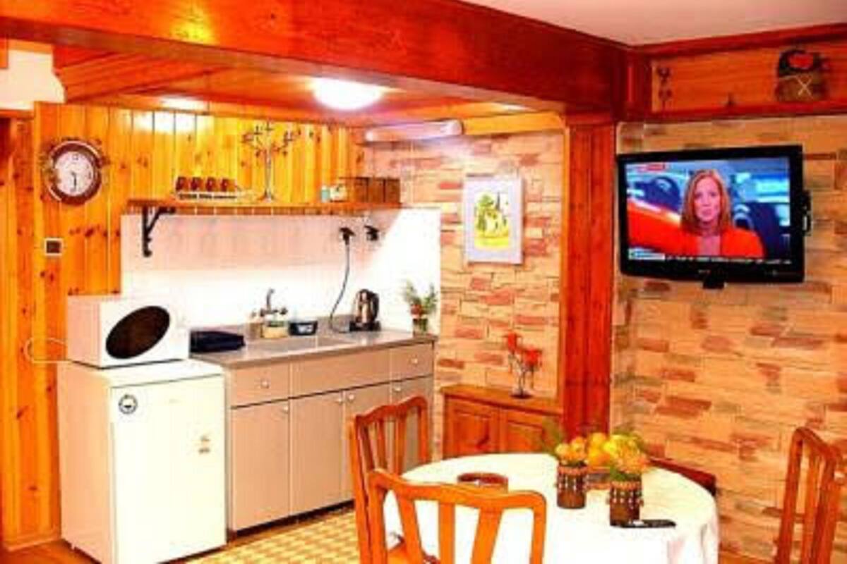 A compact kitchen with wooden cabinets, a small refrigerator, and a dining area with a table and chairs.