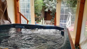 Un bain à remous avec vue sur un escalier en bois et un jardin agrémenté de différentes plantes.