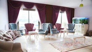 Una sala de estar con sofá, sillones, una mesa de centro y un acuario.