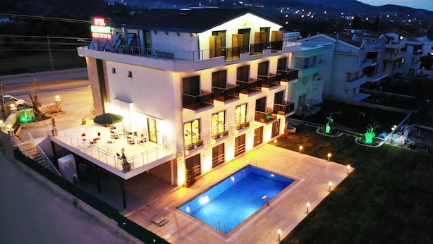 Un hotel de varios pisos con bar en la azotea, piscina y un espacio exterior bien iluminado.